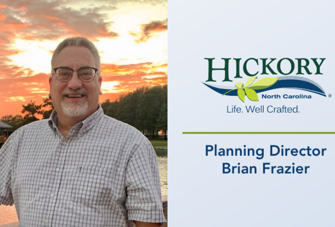 Planning Director Brian Frazier stands in front of a body of water and a sunset sky