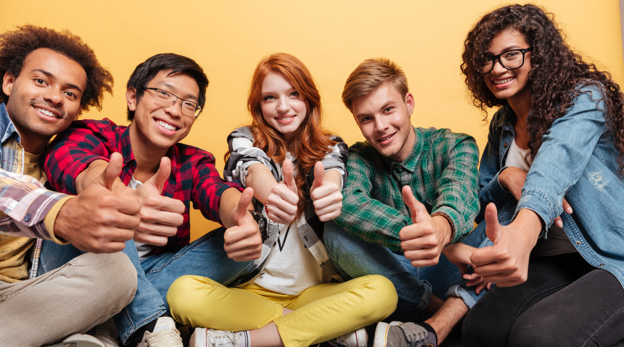 diverse group of teenagers smiling and giving thumbs up
