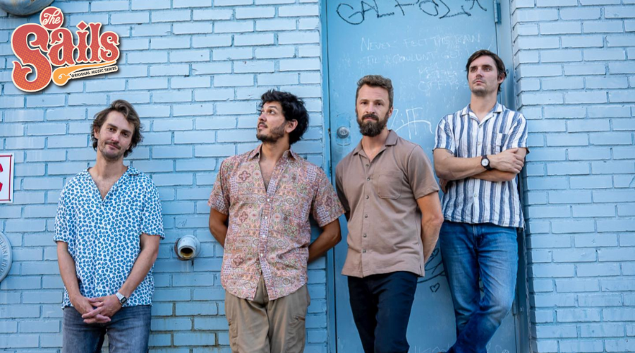 Band members of Random Animals stand against a blue brick wall